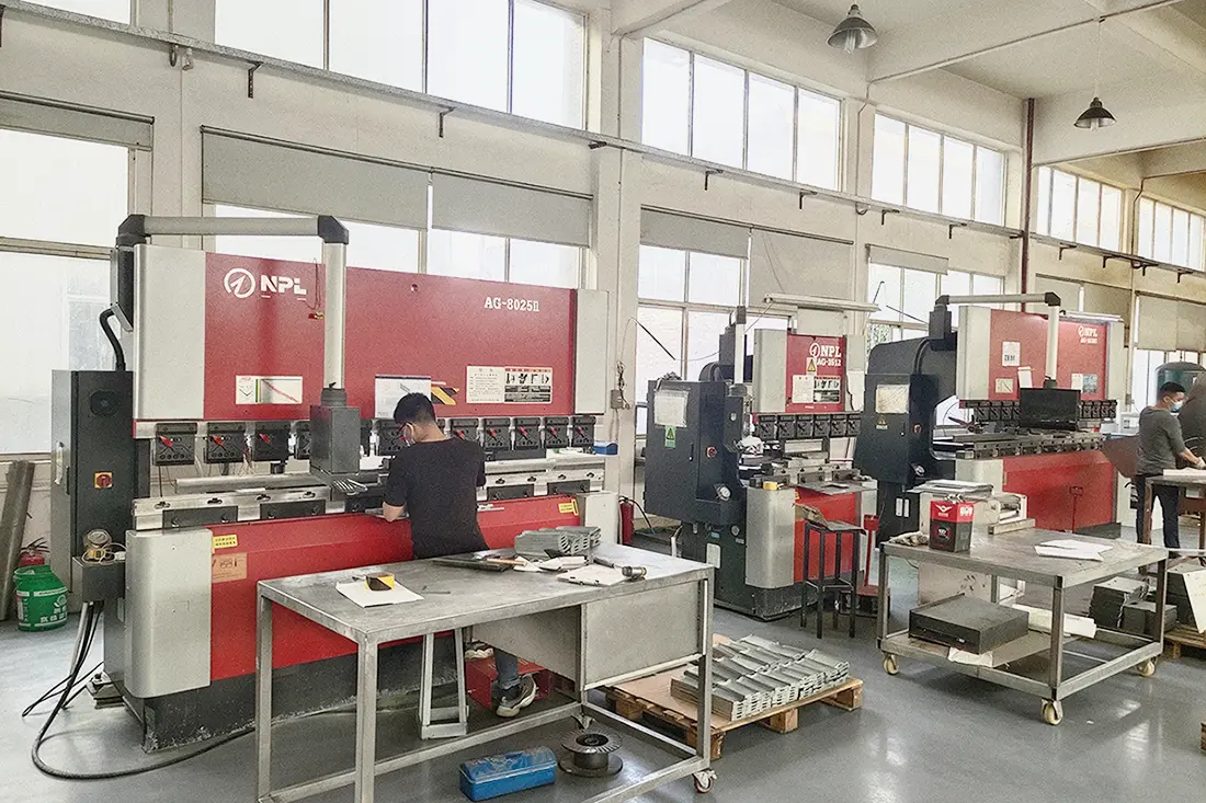 Workers operate CNC bending machines for precision sheet metal forming in factory workshop