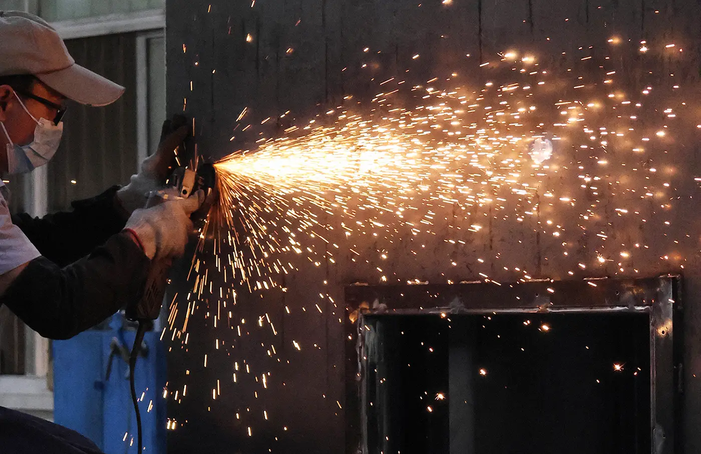 Skilled worker deburring and finishing custom sheet metal components at factory