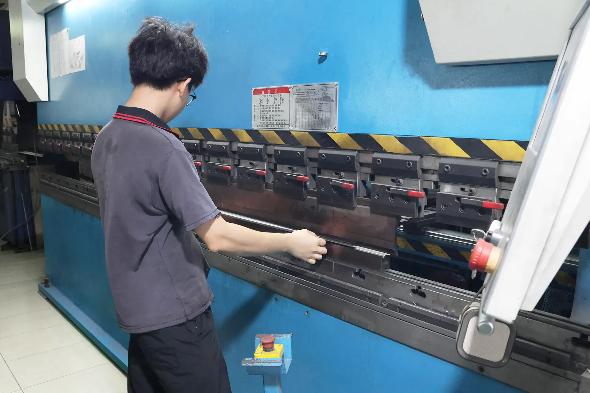 Worker operating CNC press brake for precision sheet metal bending