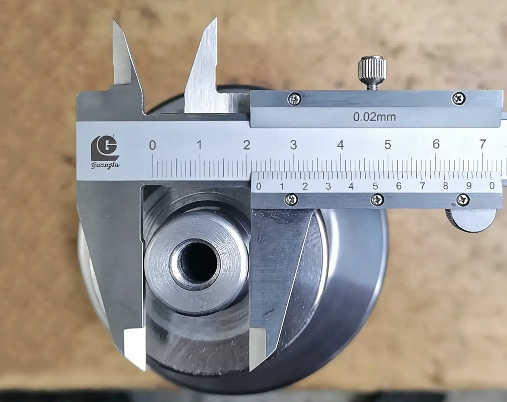 Vernier caliper measuring the dimensions of a custom-machined metal component during quality inspection