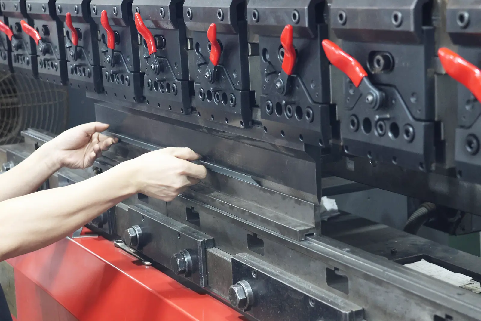 Worker operating CNC press brake for precision sheet metal bending fabrication