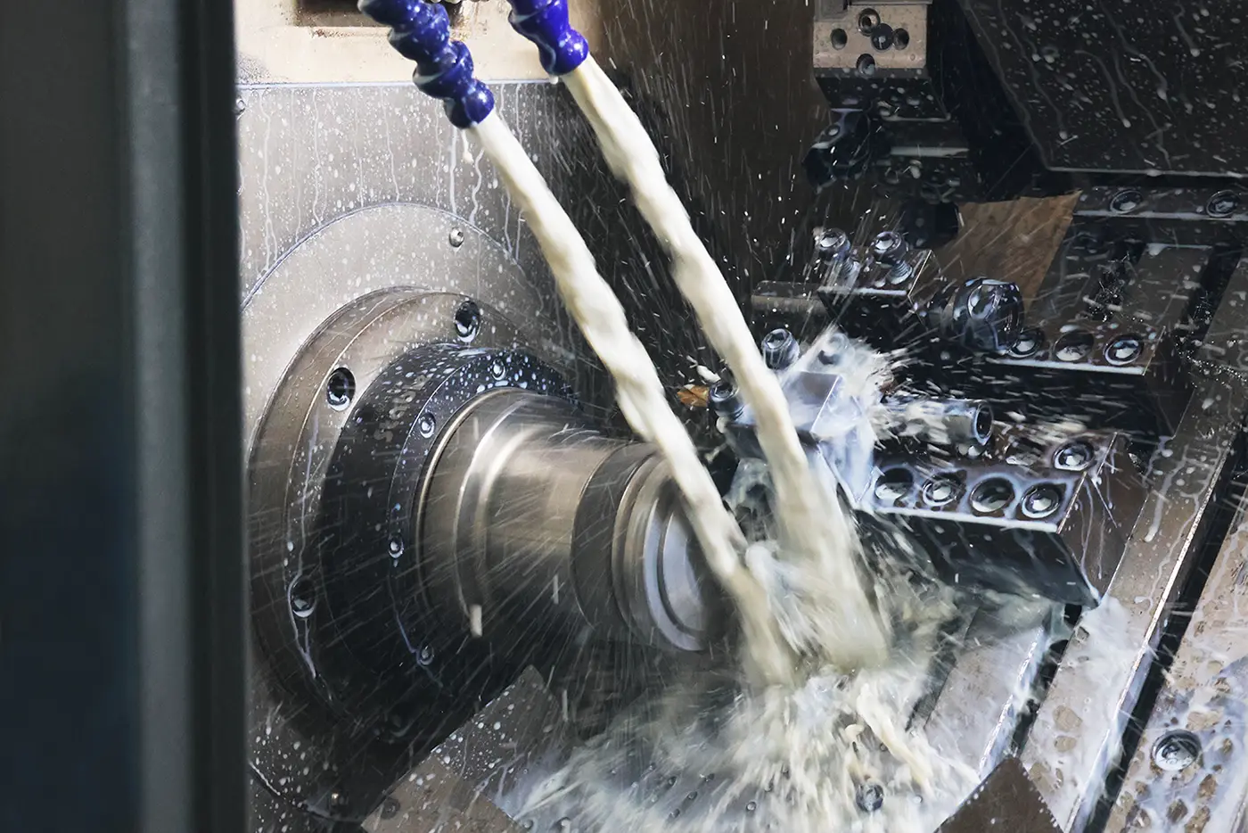 CNC lathe turning a metal part with coolant