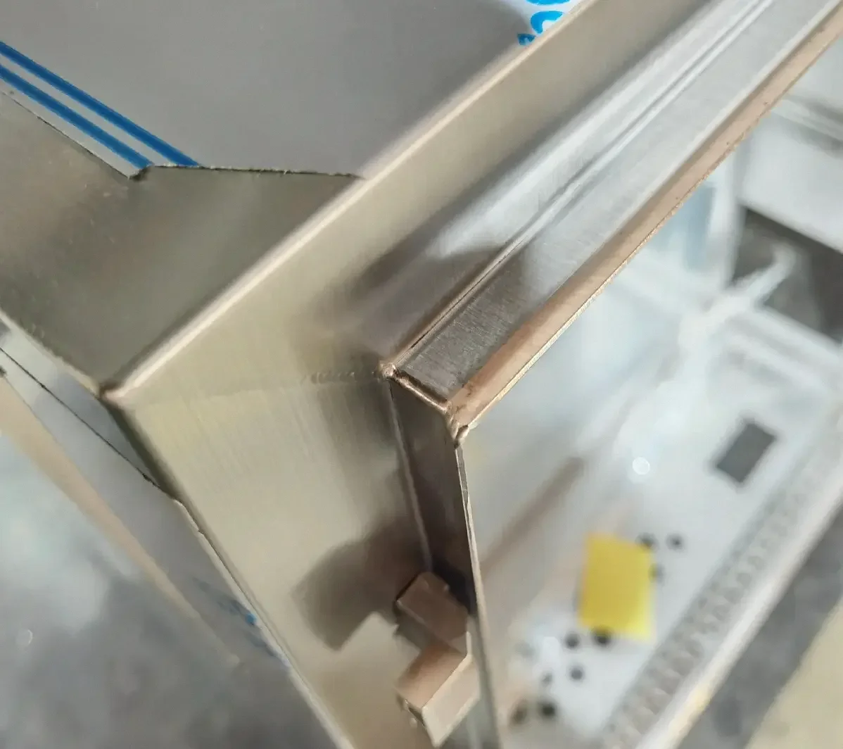 Sheet-metal enclosure corner showing the accessible area around a welded seam.