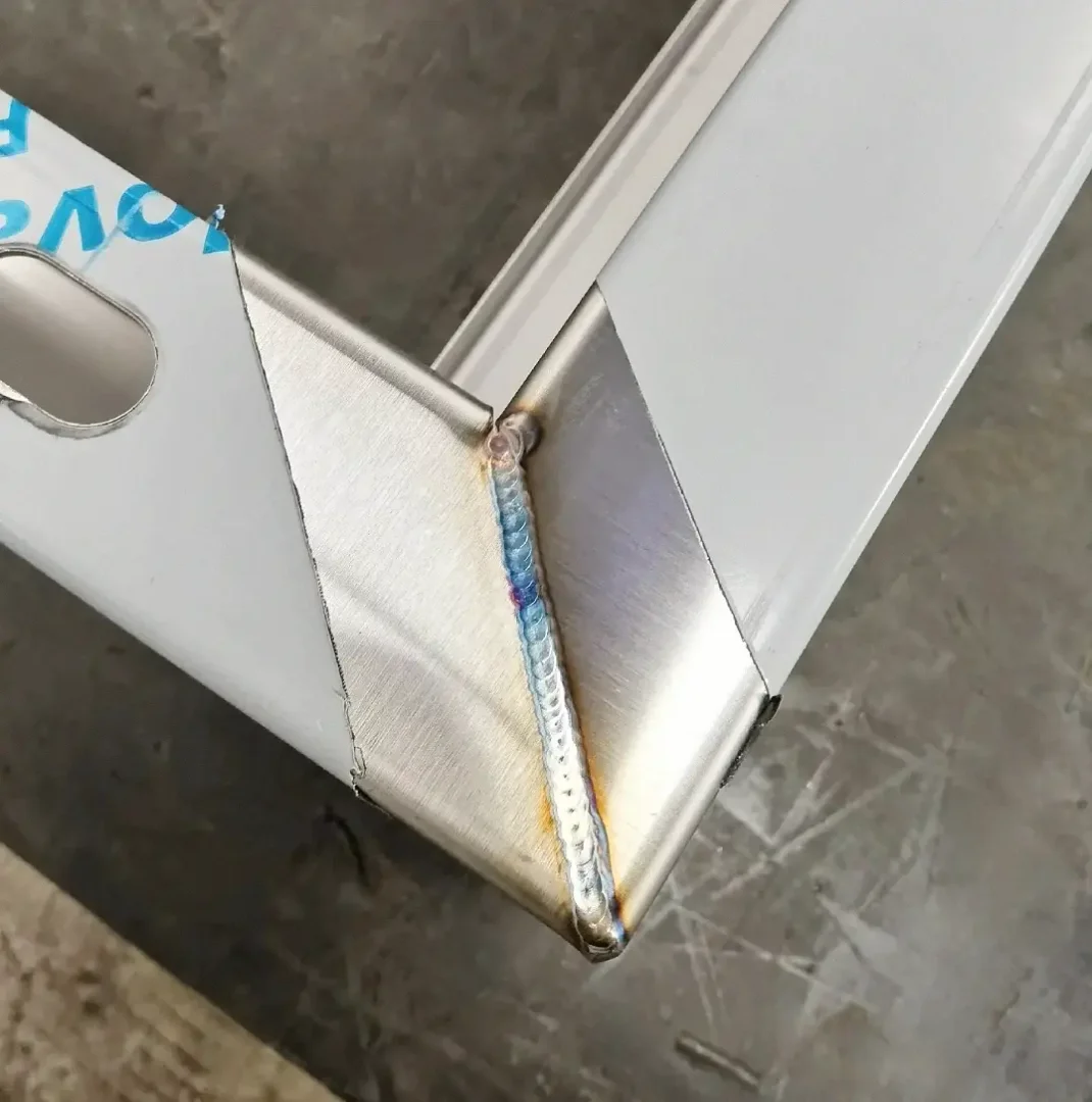 Stainless-steel enclosure corner with a welded vertical seam and protective film.