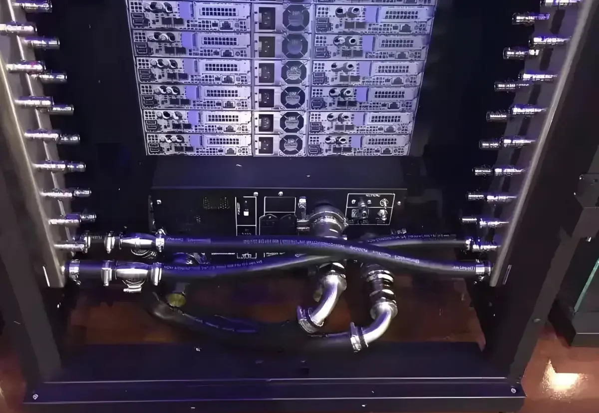 Rear view of a populated liquid-cooled AI server rack showing liquid distribution connections, hose routing, and the lower rear service area.