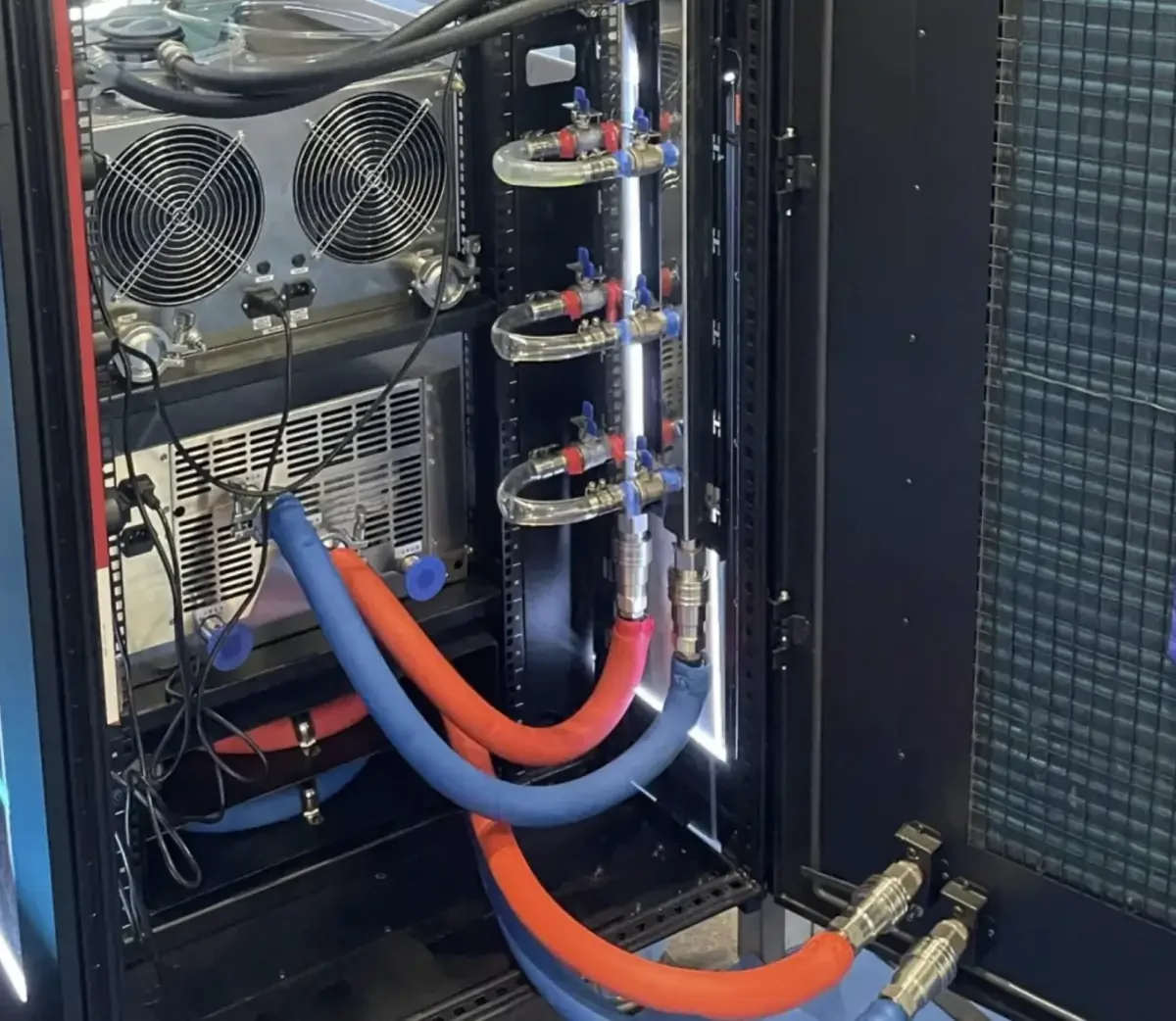 Open liquid-cooled server rack showing hose routing, liquid distribution hardware, valves, an open rear door, and cabinet airflow hardware.